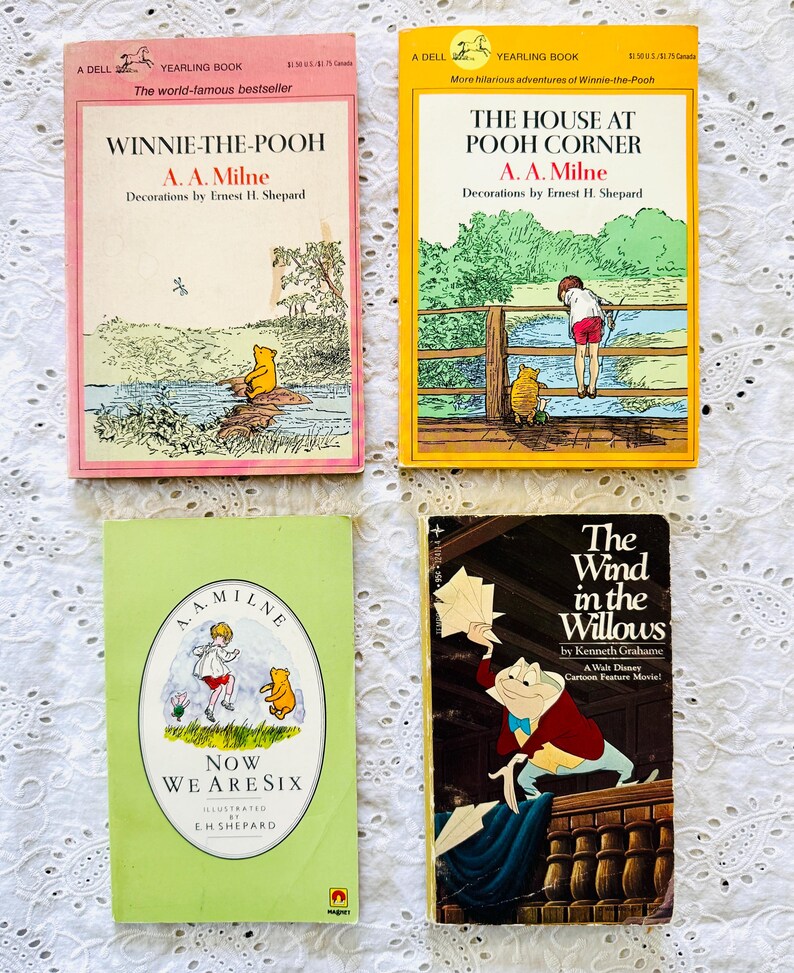 Puede incluir: Cuatro libros de bolsillo antiguos que incluyen Winnie-the-Pooh con portada rosa, The House at Pooh Corner con portada amarilla, Now We Are Six con portada verde claro y The Wind in the Willows con portada oscura y un personaje de rana.