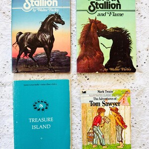 Puede incluir: Cuatro libros antiguos que incluyen The Black Stallion y The Black Stallion and Flame de Walter Farley, Treasure Island de Junior Great Books Series Three Vol. 6, y The Adventures of Tom Sawyer de Mark Twain con una ilustraci&oacute;n en la portada.