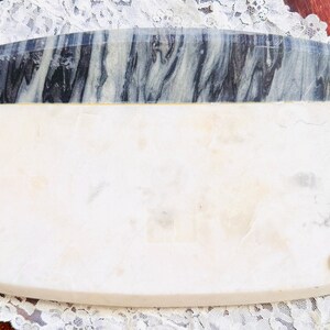 May include: Rectangular marble serving tray with a white base and a gray and black marbled top section. The tray has four small, round feet and is set on a white lace doily.