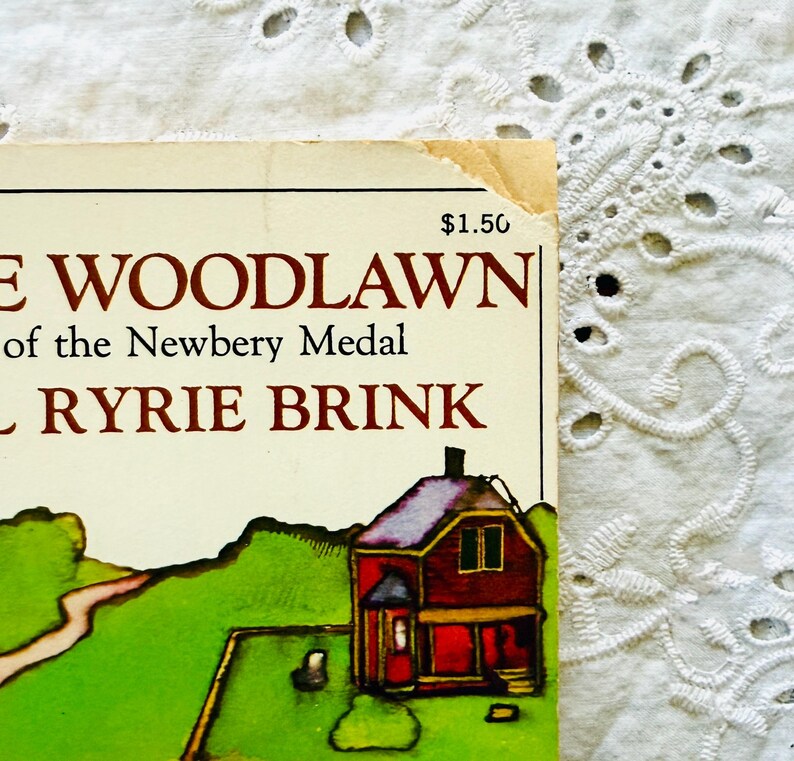 Puede incluir: Una portada de libro con el texto CADDIE WOODLAWN, of the Newbery Medal, y CAROL RYRIE BRINK. La portada muestra una casa roja con techo oscuro sobre un paisaje verde con un camino. En la esquina superior derecha se ve el precio de 1,50 $.