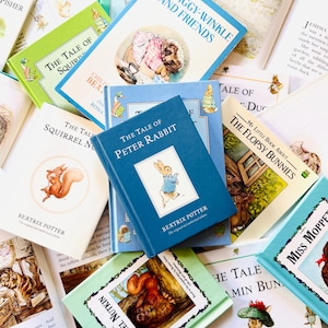 May include: A collection of Beatrix Potter books featuring titles such as The Tale of Peter Rabbit, The Tale of Squirrel Nutkin, and The Flopsy Bunnies. The books have colorful covers with illustrations of animals and text in various fonts.