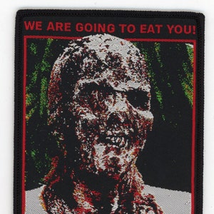 May include: A black and red embroidered patch with a zombie face and the text "WE ARE GOING TO EAT YOU! ZOMBIE ...THE DEAD ARE AMONG US!"