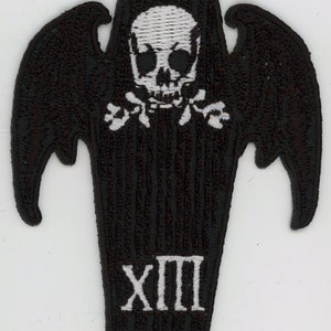 May include: Black embroidered patch with a white skull and crossbones on a coffin with bat wings. The coffin has the Roman numeral XIII on the bottom.