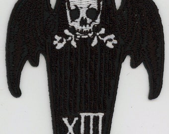 May include: Black embroidered patch with a white skull and crossbones on a coffin with bat wings. The coffin has the Roman numeral XIII on the bottom.