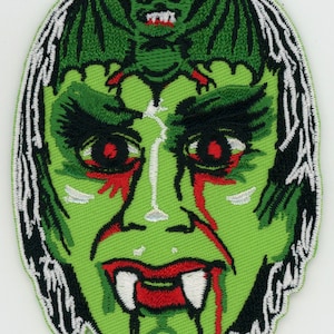 May include: Green embroidered patch of a monster's face with fangs and dripping blood. A green bat with red eyes is perched on the monster's forehead.