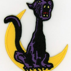 May include: Purple and black embroidered patch of a black cat sitting on a yellow crescent moon.