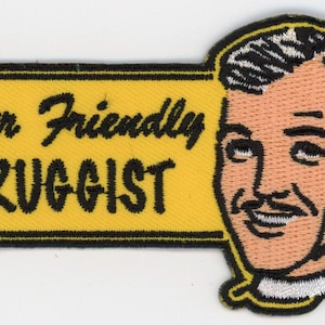 May include: A yellow and black embroidered patch with the text "Your Friendly Druggist" and a cartoon image of a man with a mustache.