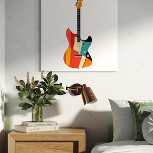 Może przedstawiać: Kolorowy nadruk artystyczny gitary w stylu retro. Gitara ma czerwone, pomarańczowe, ż&oacute;łte, turkusowe i czarne akcenty. Grafika jest wyświetlana na białym pł&oacute;tnie, dodając wibracji każdemu pomieszczeniu.