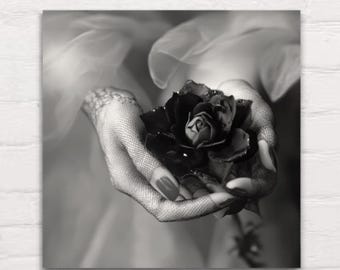 May include: A black rose held in gloved hands. The rose is in full bloom and the hands are wearing delicate lace gloves.
