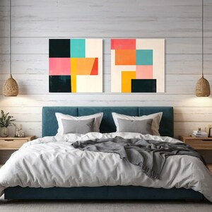 Puede incluir: Dos pinturas geom&eacute;tricas abstractas con fondo blanco y bloques de colores rosa, naranja, amarillo, turquesa y negro. Las pinturas est&aacute;n colgadas sobre una cabecera de color turquesa y una cama blanca con una manta gris.