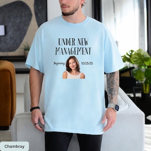 a man wearing a t - shirt that says under new management