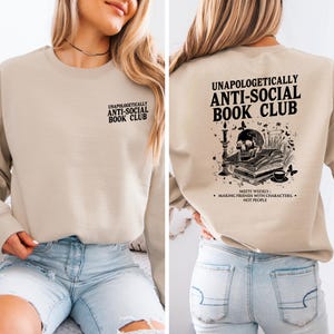 a woman wearing a beige sweatshirt with text and graphics on the back.