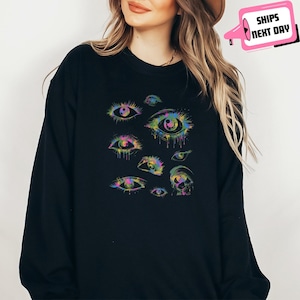 a woman wearing a black sweatshirt with colorful eyes on it