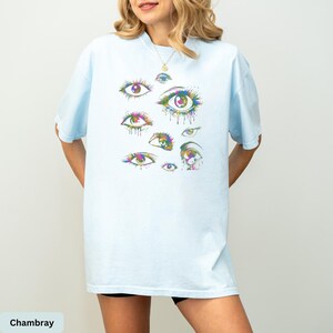 a woman wearing a blue t - shirt with an eye print on it