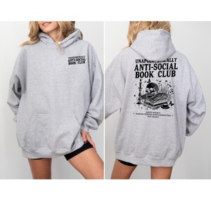 A woman wearing a grey hoodie with text and graphics on the back.