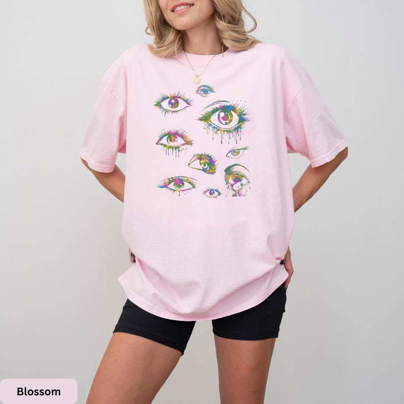 a woman wearing a pink shirt with rainbow eyes on it