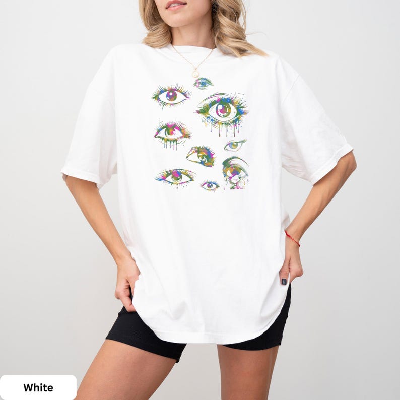 a woman wearing a white t - shirt with colorful eyes on it