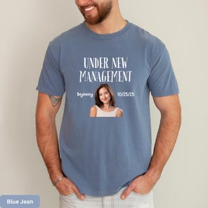 a man wearing a t - shirt that says under new management