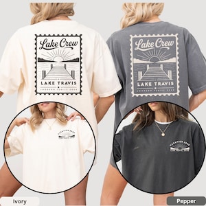May include: An ivory and a pepper gray t-shirt, each featuring a large back graphic of a postage stamp design with a lake dock, sun, and the text "Lake Crew LAKE TRAVIS JOHNSON FAMILY 2026". The front chest displays a smaller matching sun graphic.