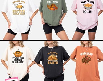 May include: A collection of six oversized t-shirts in various colors, each with a unique Thanksgiving-themed graphic and text. Designs include butter, a cornucopia, a pie, a pumpkin, a roasted turkey, and a flexing turkey. The shirts are displayed on models.