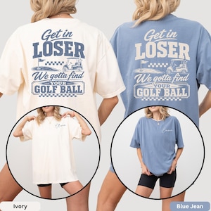 May include: Two oversized t-shirts in ivory and blue jean colors. The back features a graphic with a golf cart, a flag, and the text "Get in LOSER We gotta find YOUR GOLF BALL". The front left chest area displays a name in cursive script.
