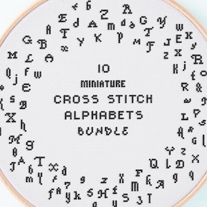 May include: A round embroidery hoop with a white fabric featuring a cross-stitch alphabet design. The text "10 Miniature Cross Stitch Alphabets Bundle" is centered. The design includes various black stitched letters and numbers.