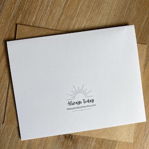 May include: A white rectangular greeting card featuring a black sunburst graphic and the text Always Today followed by the URL Alwaystodayshop.etsy.com, positioned on top of a brown kraft paper envelope.