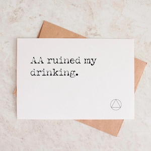 May include: A white greeting card with the text "AA ruined my drinking" in black, with a small triangle symbol. The card is on top of a brown envelope.