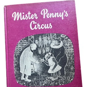 May include: Vintage hardcover book titled "Mister Penny's Circus" with a magenta cover. The cover illustration features a man, a monkey, and a bear in a circus scene. The author's name, Marie Hall Ets, is printed at the bottom.