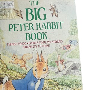 May include: The Big Peter Rabbit Book cover features a colorful illustration of Peter Rabbit wearing a blue jacket and sitting on the ground. The book title is in green text and the author, Beatrix Potter, is listed below the illustration.