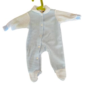 Może przedstawiać: Jasnoniebieski pajacyk dla dziecka z kołnierzykiem i długimi rękawami, zawieszony na zielonym wieszaku. Pajacyk ma zapinany na guziki prz&oacute;d i st&oacute;pki. Tkanina ma wz&oacute;r w paski.