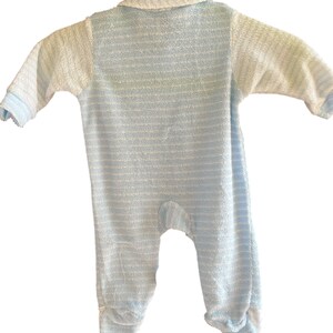 Może przedstawiać: Niemowlęcy pajacyk w niebiesko-białe paski, z długimi rękawami i zintegrowanymi st&oacute;pkami. Pajacyk ma kołnierzyk i jest wykonany z miękkiej, teksturowanej tkaniny. Klasyczny design, odpowiedni dla noworodk&oacute;w.