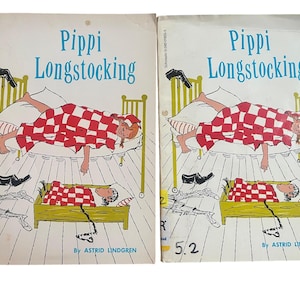 Può includere: Due copie vintage di "Pippi Calzelunghe" di Astrid Lindgren. Le copertine dei libri presentano un'illustrazione di Pippi a letto sotto una coperta a scacchi rossi e bianchi. Il titolo è in blu, con illustrazioni di scarpe e mobili.