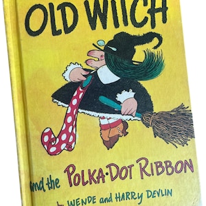 May include: A vintage children's book titled "Old Witch and the Polka-Dot Ribbon" by Wende and Harry Devlin. The cover features a cartoon witch with green hair, a black dress, and a red and white polka-dot ribbon, riding a broom.
