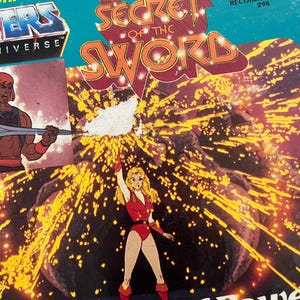 Może przedstawiać: Vintage okładka albumu winylowego dla "He-Man and the Masters of the Universe: The Secret of the Sword". Okładka zawiera ilustracje z kresk&oacute;wek i tytuł w kolorze pomarańczowym i czerwonym. Album pochodzi z Kid Stuff Records & Tapes.