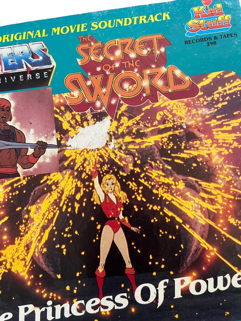 Może przedstawiać: Vintage okładka albumu winylowego dla "He-Man and the Masters of the Universe: The Secret of the Sword". Okładka zawiera ilustracje z kresk&oacute;wek i tytuł w kolorze pomarańczowym i czerwonym. Album pochodzi z Kid Stuff Records & Tapes.