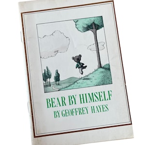 Puede incluir: Una portada de libro vintage con un borde marrón y un título verde. El título es "BEAR BY HIMSELF" de GEOFFREY HAYES. La portada presenta una ilustración en blanco y negro de un oso de peluche con una camisa a rayas verdes y blancas, balanceándose de una rama de árbol.