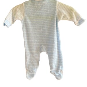 Może przedstawiać: Śpioszki dla niemowląt w niebiesko-białe paski. Śpioszki mają długie rękawy, kołnierzyk i osłony na stopy. Tkanina wydaje się być miękkim, teksturowanym materiałem.