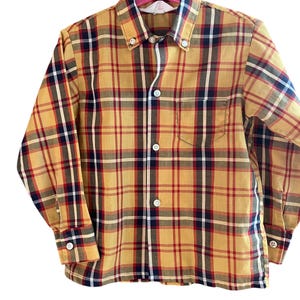 May include: A yellow, red, and black plaid long-sleeve button-down shirt.