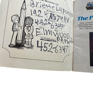 Może przedstawiać: Otwarta strona książki z sekcją zatytułowaną &bdquo;TA KSIĄŻKA NALEŻY DO:&rdquo;, wypełnioną odręcznymi informacjami. Strona zawiera ilustracje dwojga dzieci z dużym oł&oacute;wkiem. Tekst zawiera imię, nazwisko, adres i numer telefonu.