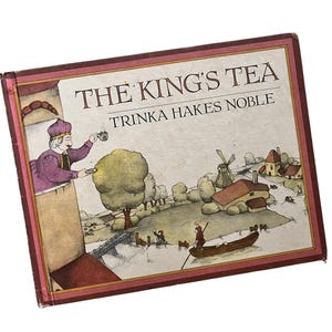 Op de afbeelding: Een vintage boek getiteld "The King's Tea" met een gedetailleerde illustratie. De omslag toont een ingelijste illustratie van een koning die thee schenkt, een windmolen en een kleine boot op een meer. Het boek heeft een bordeauxrode rand.