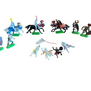 May include: A collection of toy knights and horses in various poses. The figures are painted in a variety of colors, including blue, silver, red, and black. Some knights are on horseback, while others are on foot. The toys are on green bases.