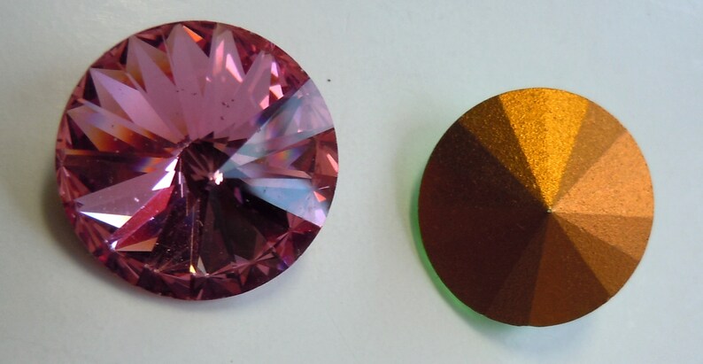 May include: Two round, faceted, decorative buttons. The button on the left is pink and the button on the right is copper.