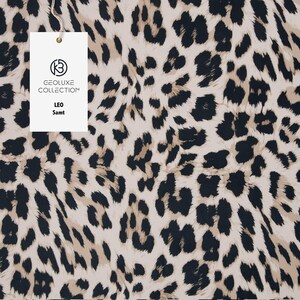 Könnte beinhalten: Ein Stoff mit Leopardenmuster in Schwarz, Beige und Creme. Ein weißes Etikett mit der Aufschrift "GEOLUXE COLLECTION" und den Worten "LEO Samt" ist angebracht.