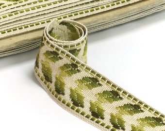 May include: A beige and green woven trim with a leaf pattern. The trim is folded and rolled up.