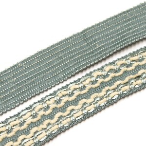 May include: Two pieces of trim, one with a simple woven design and the other with a more intricate design featuring a white thread and silver accents.