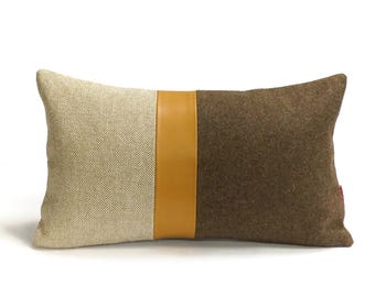 May include: A rectangular throw pillow with a brown, beige, and mustard yellow striped design. The pillow is made of a soft, textured fabric.