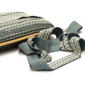May include: A roll of blue and white striped trim with a beige cardboard backing. The trim is woven and has a textured surface.