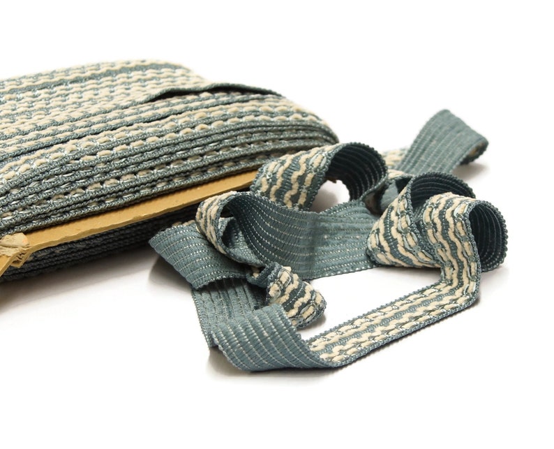 May include: A roll of blue and white striped trim with a beige cardboard backing. The trim is woven and has a textured surface.