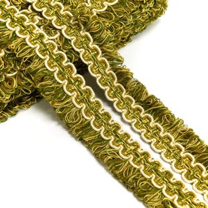 May include: Green and white braided trim with a fringe. The trim has a repeating pattern of loops and is perfect for adding a decorative touch to home decor projects.